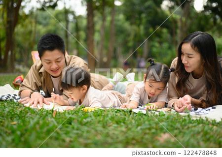 Cheerful family enjoys an outdoor picnic on a sunny day. Parenting, outdoor leisure and family bonding concept 122478848
