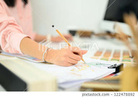 Close up of female designer hand sketching a detailed interior layout at her desk 122478892
