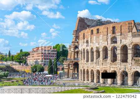 Crowds gather near the Colosseum in Rome, Italy, under a bright blue sky. This iconic landmark showcases ancient architecture and attracts tourists year-round with its historical significance. Crowds gather near the Colosseum in Rome, Italy, under a bright blue sky. This iconic landmark showcases ancient architecture and attracts tourists year-round with its historical significance. 122479342