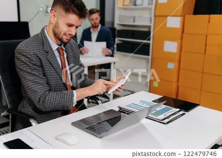 Businessman calculating bills and taxes looking at calculator gesturing with hands sitting at work desk. Businessman calculating bills and taxes looking at calculator gesturing with hands sitting at work desk. 122479746