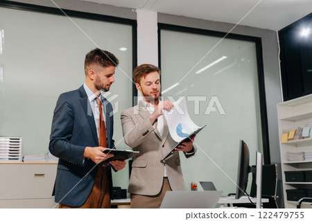 Diverse professionals collaborate on project analysis with financial graphs. Strategic teamwork and insights drive company growth and success. Diverse professionals collaborate on project analysis with financial graphs. Strategic teamwork and insights drive company growth and success. 122479755