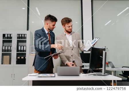 Diverse professionals collaborate on project analysis with financial graphs. Strategic teamwork and insights drive company growth and success. 122479756