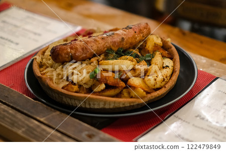 A plate of food with a sausage and potatoes on it 122479849