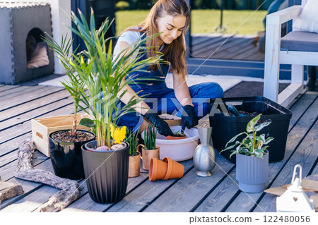European female enjoy her hobby gardening at terrace outdoor Casual lifestyle series in modern scandinavian interior. Leisure, lifestyle, mental health, real life concept. 122480056
