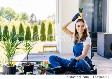 Having Fun Growing Plants Concept. Playful young female holds small succulents plants in pots enjoys her time at home, working at terrace with plants. 122480067