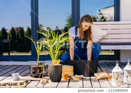 Happy woman gardener in work gloves is transplanting different plants flowers in pots, on terrace. Summer lifestyle, life in a country house concept. 122480094