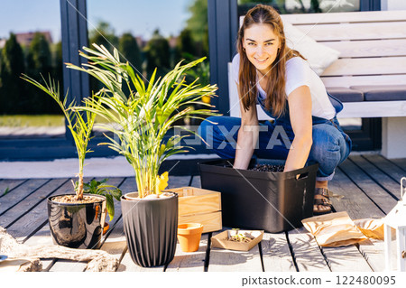 Happy woman gardening and repotting plant at the backyard. 122480095