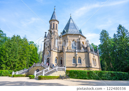 Visitors explore the elegant Schwarzenberg Tomb in Domanin, surrounded by lush greenery. The striking architecture stands out against the clear blue sky, inviting exploration. 122480336