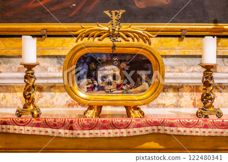 The remains of Saint Valentine are displayed in a glass relic at Basilica of Santa Maria in Cosmedin in Rome, surrounded by decorative candles and ornate furnishings, reflecting a sacred atmosphere. The remains of Saint Valentine are displayed in a glass relic at Basilica of Santa Maria in Cosmedin in Rome, surrounded by decorative candles and ornate furnishings, reflecting a sacred atmosphere. 122480341