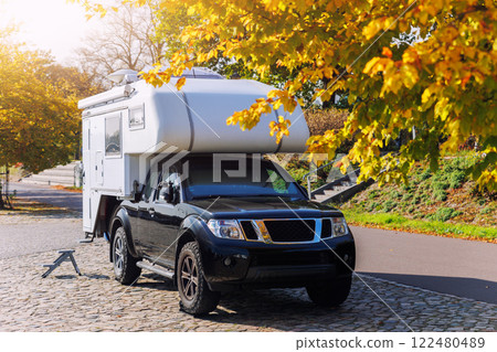 Scenic view pick-up off-road expedition truck parked many modern campervan recreational motor home vehicle camper site Magdeburg city. Motorhome campground station travel destination. RV lifestyle 122480489