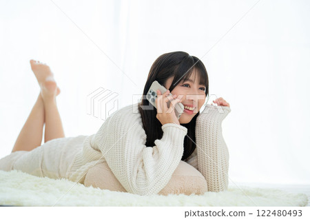 Japanese woman lying face down talking on the phone 122480493