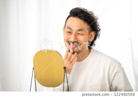 Japanese man checking his skin in the mirror Japanese man checking his skin in the mirror 122480508