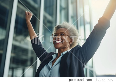 Triumphant and empowered female businesswoman celebrating her corporate success with joy and enthusiasm in a modern office building. Showcasing her achievement. Determination 122480889