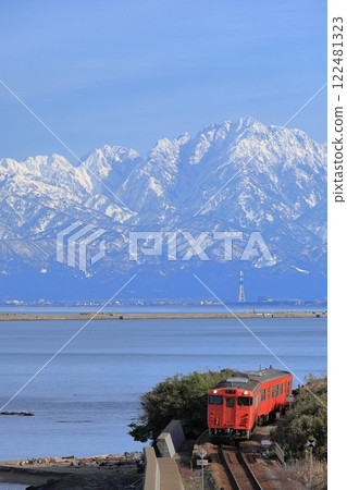 以立山山脈為背景的冰見線列車在天晴海岸行駛 122481323
