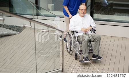 Elderly person in wheelchair and caregiver standing on stairs Elderly person in wheelchair and caregiver standing on stairs 122481767