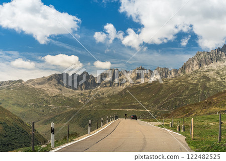 Cyclist and car driving on the Furka Pass road in the Swiss Alps, Canton of Uri, Switzerland Cyclist and car driving on the Furka Pass road in the Swiss Alps, Canton of Uri, Switzerland 122482525