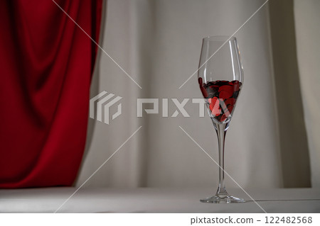 Wine glass with heart confetti on cream and red silk background. Minimalist lowkey holiday photo for Valentines 122482568