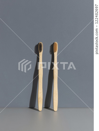 Two biodegradable bamboo toothbrushes on a grey background with hard shadow closeup, mockup Two biodegradable bamboo toothbrushes on a grey background with hard shadow closeup, mockup 122482697