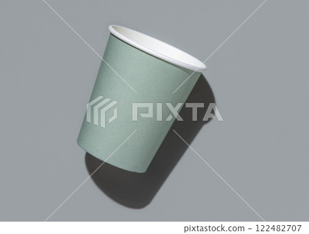 Disposable light green paper cup on a grey with hard shadow top view , mockup. Sustainable lifestyle Disposable light green paper cup on a grey with hard shadow top view , mockup. Sustainable lifestyle 122482707