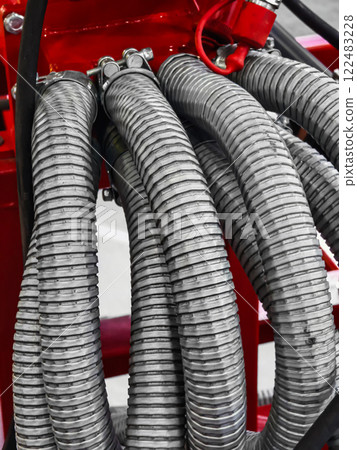 Detailed view of flexible hoses connected to industrial equipment in a workshop setting during daylight hours 122483228