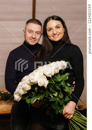 Happy couple holding a large bouquet of white roses Happy couple holding a large bouquet of white roses 122483334
