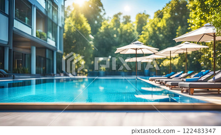 Beautiful modern outdoor swimming pool with clear clean blue water with white sun loungers on the sides 122483347