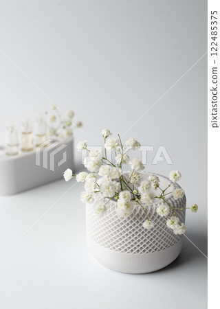 A small artificial plant with vibrant green leaves sits in a textured white pot against a clean white background A small artificial plant with vibrant green leaves sits in a textured white pot against a clean white background 122485375