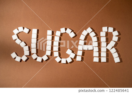 Word sugar made from sugar white cubes on brown background. Word sugar made from sugar white cubes on brown background. 122485641