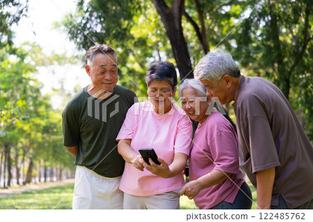 Group of happy Senior Retirement Using Smartphone and laughing outdoors at the park after a workout and spending time together, concepts about the elderly, seniority, and wellness aging 122485762