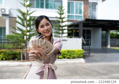 Portrait of happy attractive Asian women holding a lot of banknotes in front of home to celebrate and Pay the final installment of the house, Loans for real estate concept, Smiling young successful 122486129