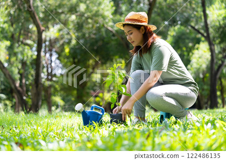 Happy young Asian woman volunteer holding a sapling to plant forests, people and ecology concept, environment Earth Day In the hands of trees growing seedlings, love of nature and care concept Happy young Asian woman volunteer holding a sapling to plant forests, people and ecology concept, environment Earth Day In the hands of trees growing seedlings, love of nature and care concept 122486135