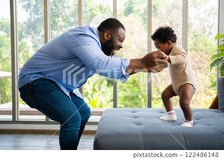 Portrait Of Happy African American Dad With Cute Little Baby Girl on couch at home in the living room, caring father smiling and amusing his girl while sitting on the couch, happy family Portrait Of Happy African American Dad With Cute Little Baby Girl on couch at home in the living room, caring father smiling and amusing his girl while sitting on the couch, happy family 122486148