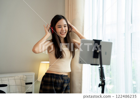 Asian women and beautiful bloggers wear headphones dancing videos by smartphone cameras. Creator vlogger talent dancing enjoys hobby content recording show video sharing on social media. Asian women and beautiful bloggers wear headphones dancing videos by smartphone cameras. Creator vlogger talent dancing enjoys hobby content recording show video sharing on social media. 122486235