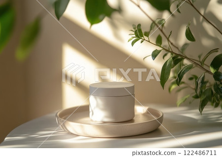 A white jar with a lid sits on a white plate on a table A white jar with a lid sits on a white plate on a table 122486711