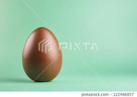 A chocolate egg is sitting on a green background 122486857