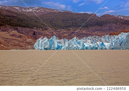 Distant view of Grey Glacier flowing into Lago Grey surrounded by mountains in Torres del Paine 122486958