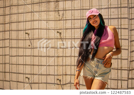 Young millennial smiling latin woman with a pink cap and long hair on a sunny day Young millennial smiling latin woman with a pink cap and long hair on a sunny day 122487583