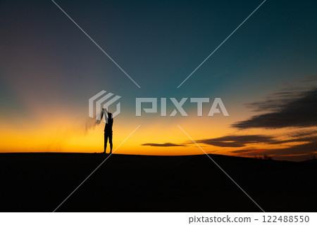 Silhouette of a Person Throwing Sand into the Air at Sunset. Saudi Arabia. Safari 122488550