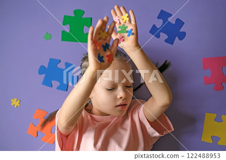 A thoughtful sad lonely girl with pieces of colored puzzles in her hands. Intellectual development of education. Problems of social behavior of children with autism 122488953