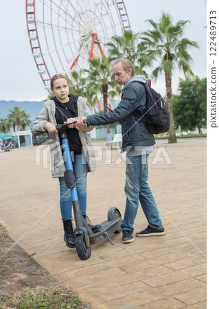 Family walking around the city with electric scooters. Father and child girl Family walking around the city with electric scooters. Father and child girl 122489713