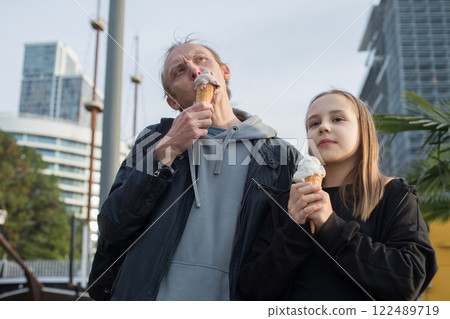 Man and child girl eating ice cream on the street, outdoor portrait 122489719