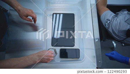 Top View on Passengers Placing Personal Items in Plastic Tray for Screening before Boarding Flight Top View on Passengers Placing Personal Items in Plastic Tray for Screening before Boarding Flight 122490293
