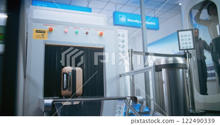 Airport Security Checkpoint: Passenger Places Suitcase on X-ray Conveyor Belt for Baggage Screening 122490339