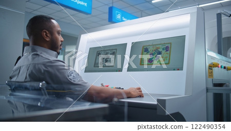 Security Officer Monitors Baggage X-ray Scanning on Computer Screens Using Modern Software 122490354