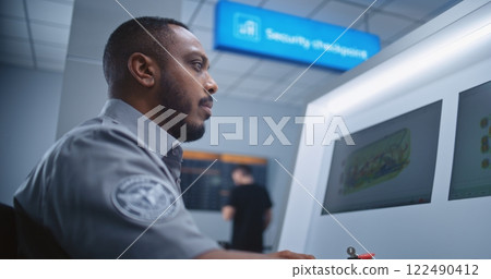 Security Officer Controls Luggage Screening on Computer Monitors Using Modern Software 122490412