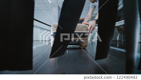 Airport Security Checkpoint: Male Tourist Places Luggage on Conveyor Belt for Screening Procedure Airport Security Checkpoint: Male Tourist Places Luggage on Conveyor Belt for Screening Procedure 122490482