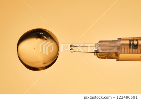 A drop of gel pours from a syringe for cosmetic procedures. A drop of gel pours from a syringe for cosmetic procedures. 122490591