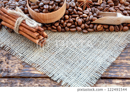 Rich aromatic coffee beans and spices arranged on rustic wooden table with natural textures 122491544