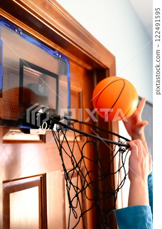Selective focus on the netting of a miniature toy basketball hoop on the door of a bedroom.  122491595
