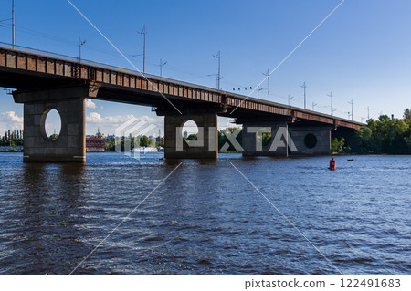 Bridge on a river against a blue sky and clouds Bridge on a river against a blue sky and clouds 122491683